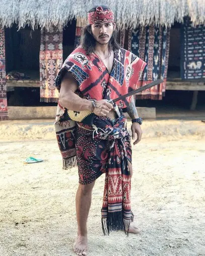 A man in full Sumbanese ceremonial dress outside a traditional house
