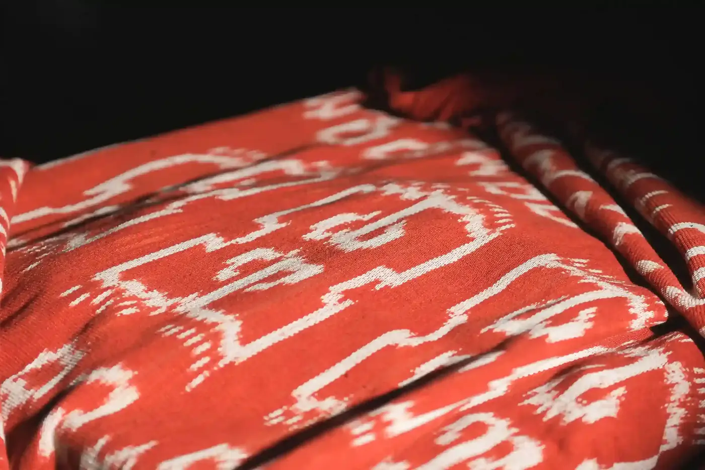 Orange-red Sumba cloth with repeating white ikat motifs