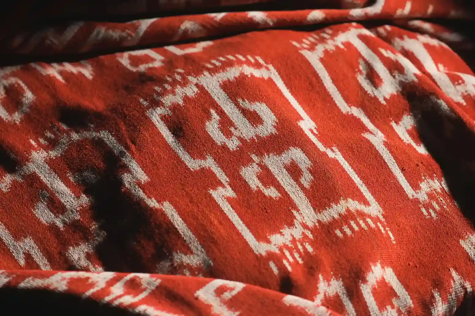Orange-red Sumba cloth with repeating white ikat motifs